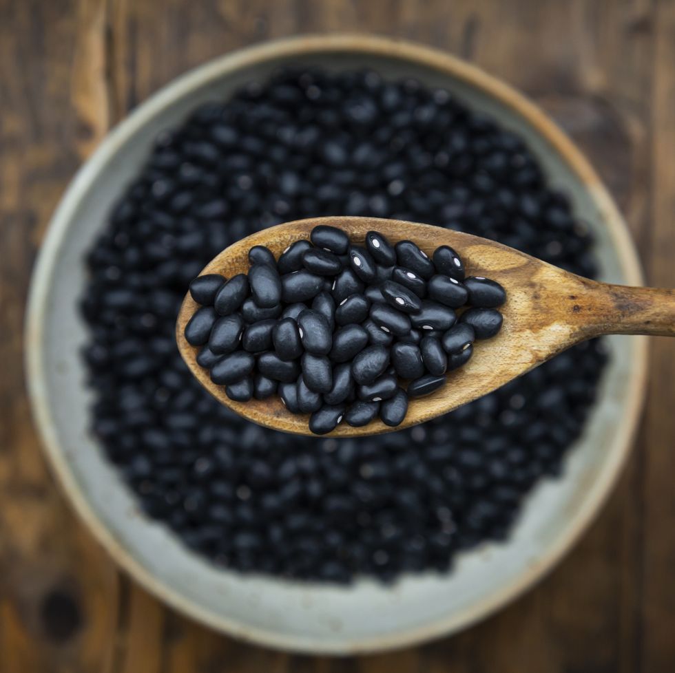 overhead view of spoon and bowl of black bean on wooden table