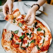 overhead view of woman's hand getting a slice of freshly made pizza and enjoying her meal in an italian restaurant