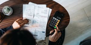 overhead view of young asian woman managing personal banking and finance at home planning budget and calculating expenses while checking her bills with calculator managing taxes and financial bills home budgeting concept of finance and economy