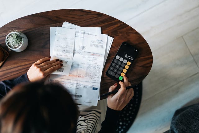 overhead view of young asian woman managing personal banking and finance at home planning budget and calculating expenses while checking her bills with calculator managing taxes and financial bills home budgeting concept of finance and economy