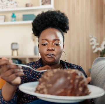 vrouw zit op de bank en kijkt naar chocoladetaart