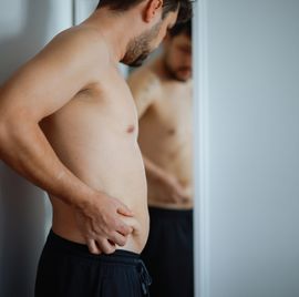overweight man checking his fat body reflection in mirror