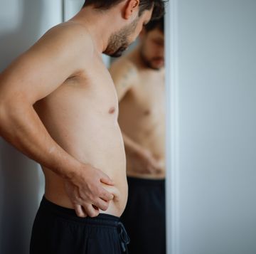 overweight man checking his fat body reflection in mirror