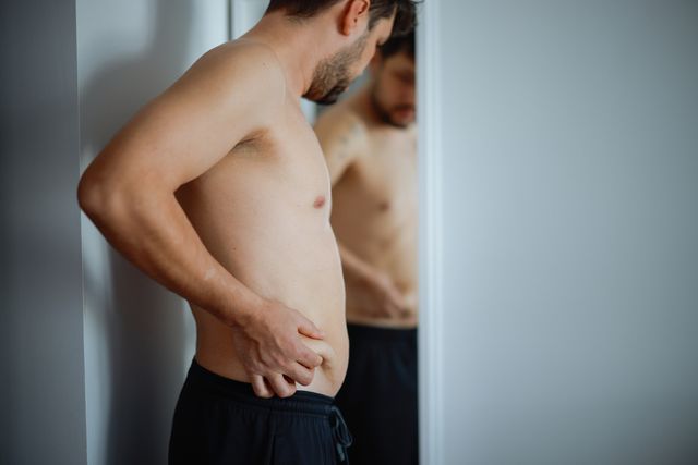 overweight man checking his fat body reflection in mirror