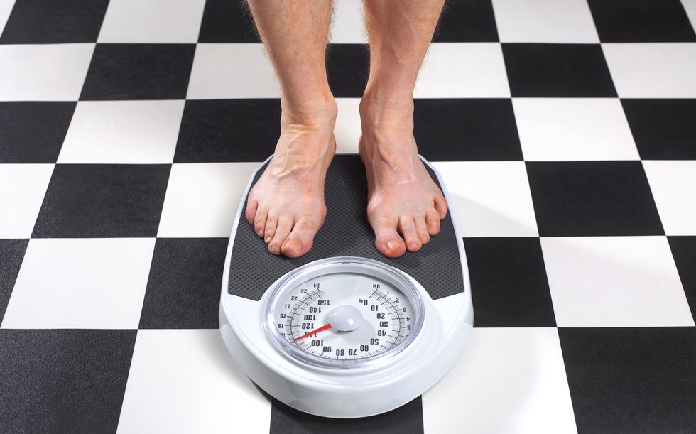 overweight man standing on bathroom scales