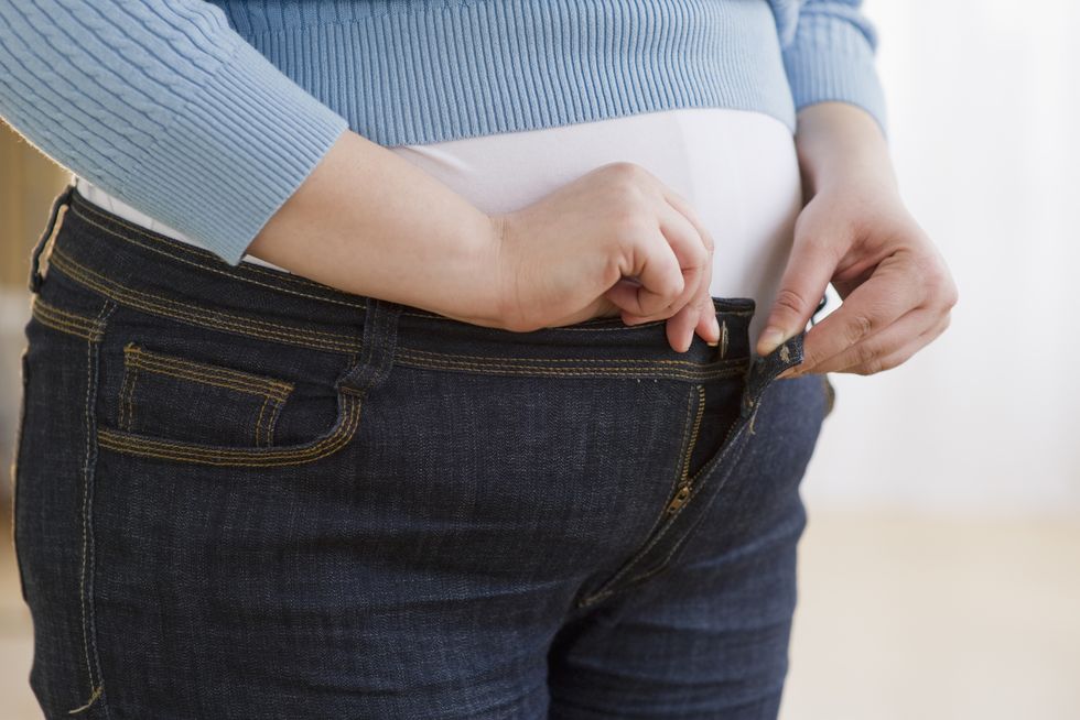 overweight woman buttoning up her jeans