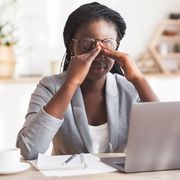 overworked black businesswoman massaging nosebridge at workplace having eyesight problem