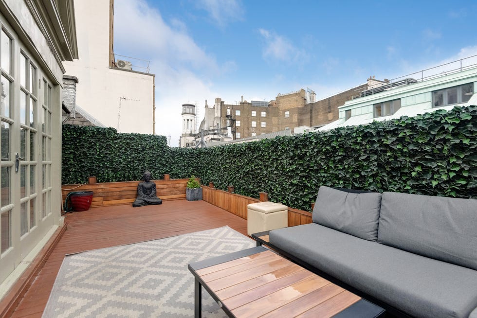 a large terrace garden with thick ivy all around and patio furniture