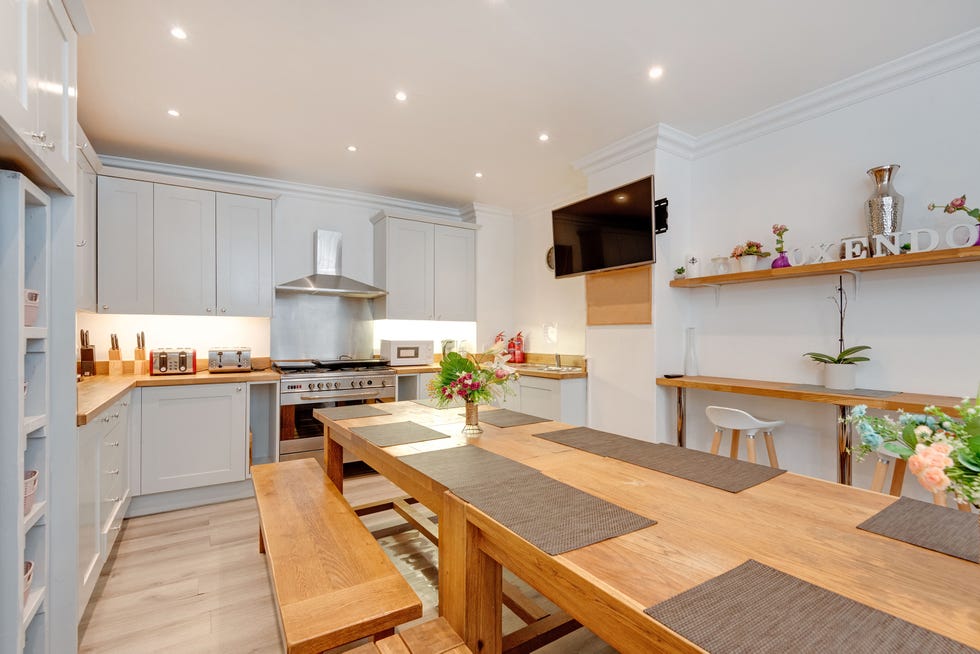 large kitchen with shaker style grey cabinetry and chrome accents and a large wooden dining table