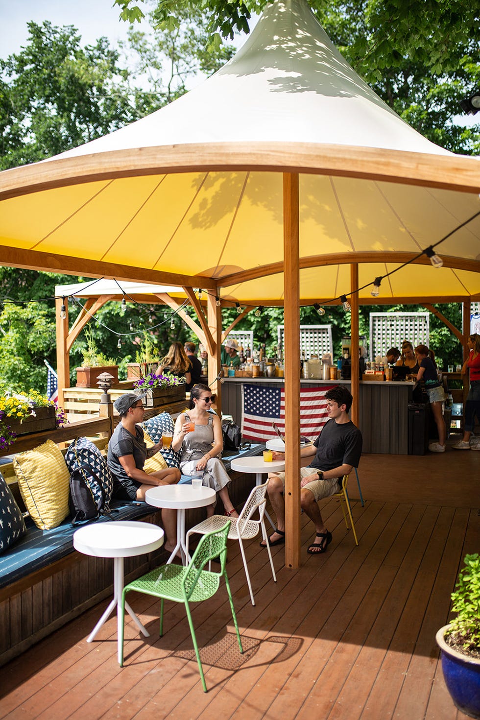 group of three friends enjoy drinks at an outdoor bar in mystic connecticut