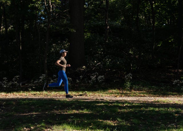 woman running along a tree lined trail