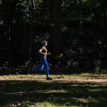 woman running along a tree lined trail