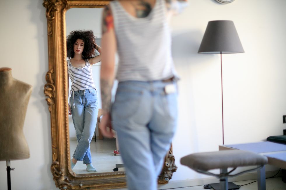 woman stares in full length mirror