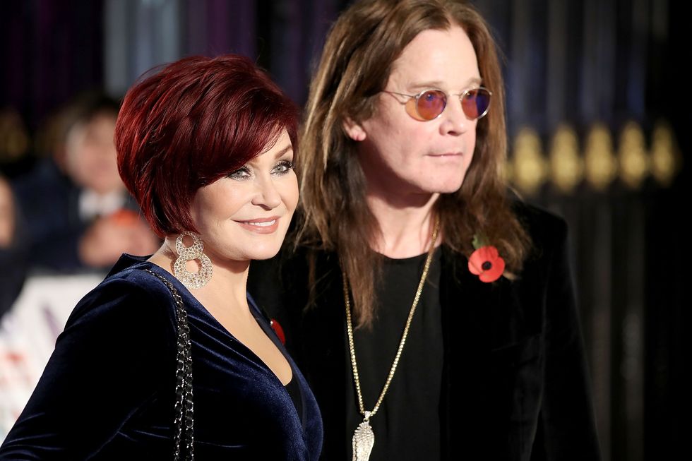 a woman and a man stand together and face right while posing for photos