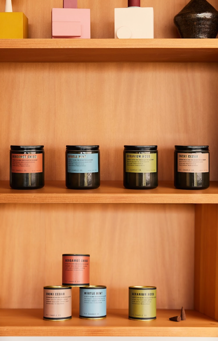 pf candle co a shelf with jars on it