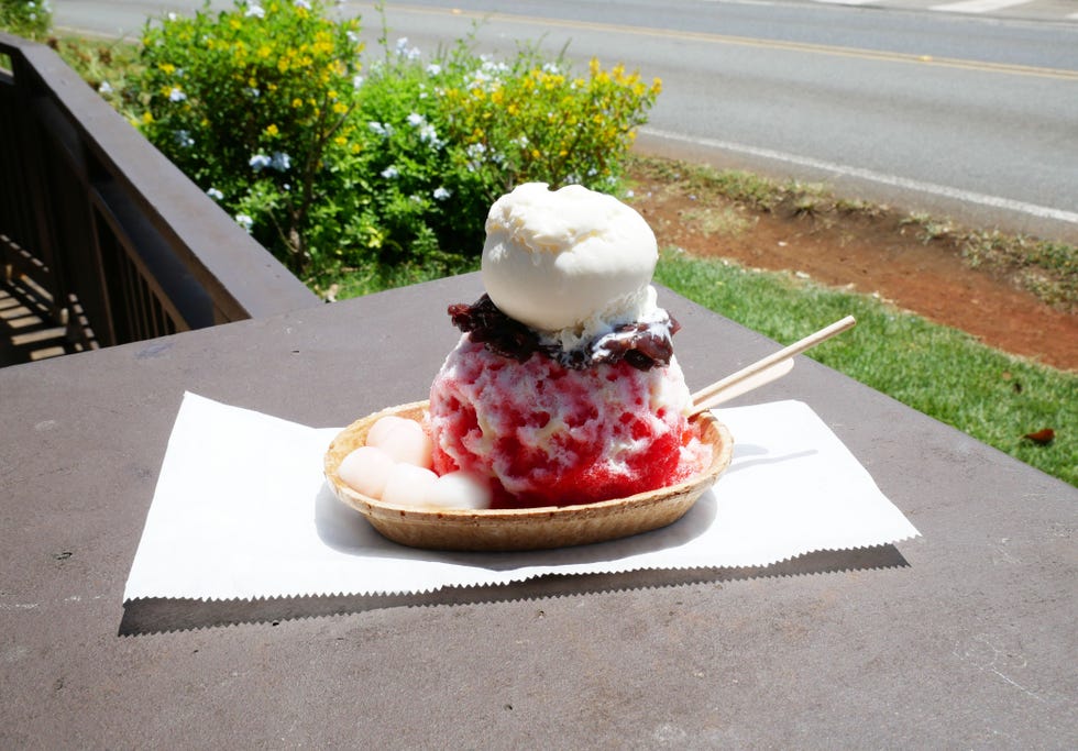 dessert bowl containing shaved ice with red syrup topped with ice cream and red bean paste alongside mochi