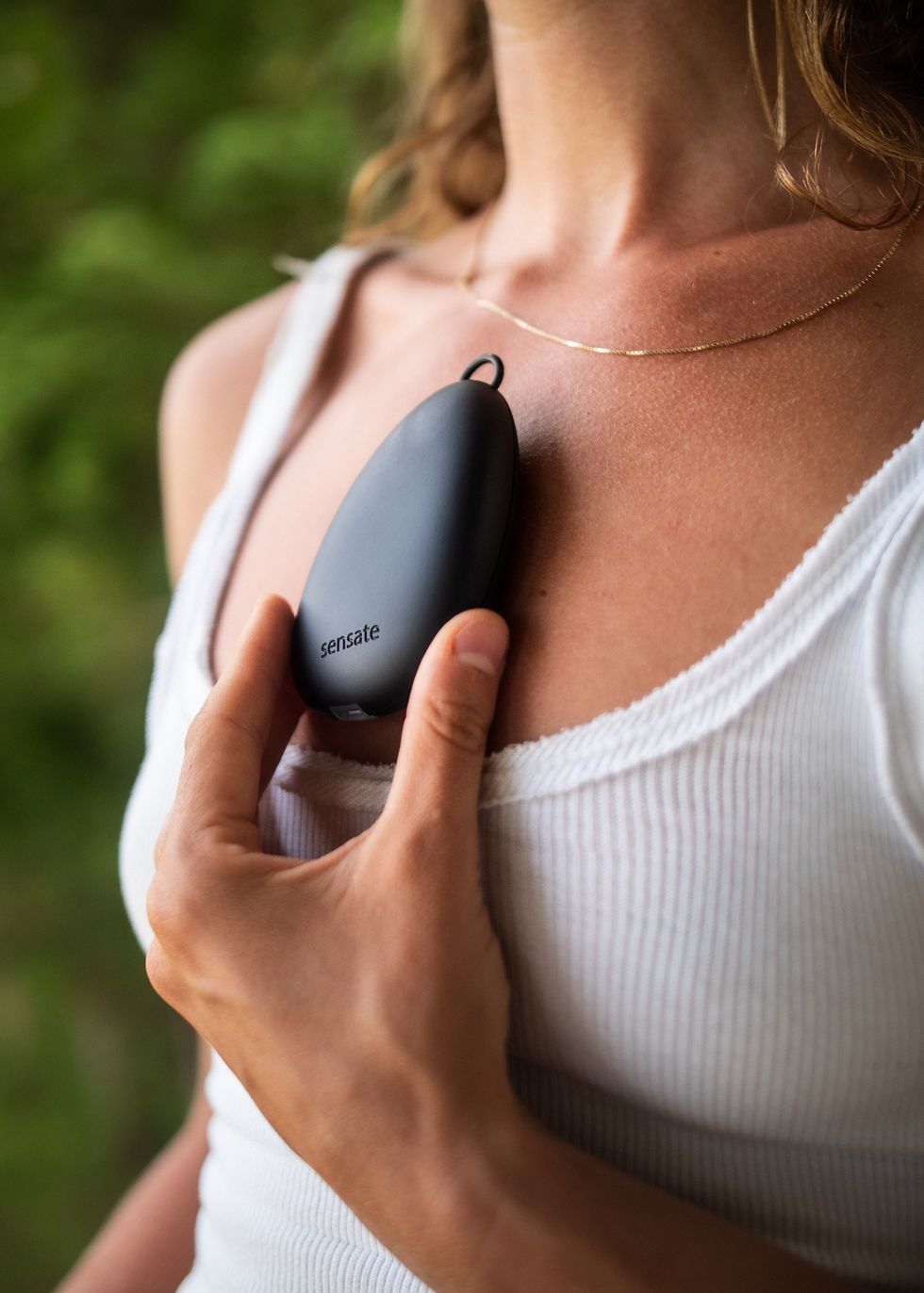 a woman holding a sensor device on her chest
