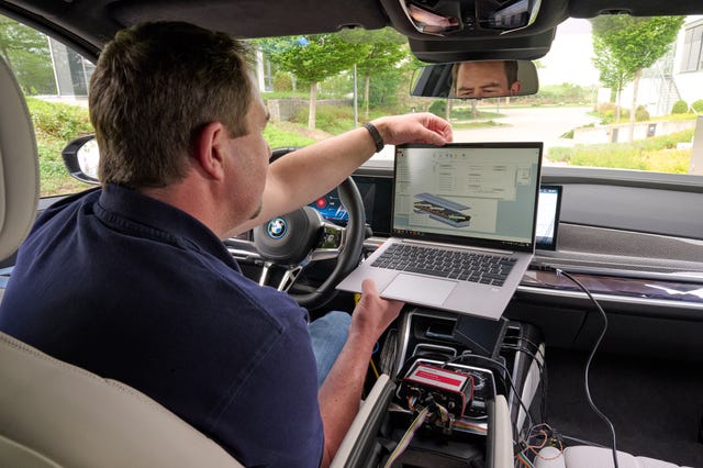 a person demonstrating a laptop displaying a software interface inside a car