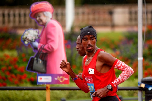 mo farah mira a un lado durante sus labores de liebre en el maratón de londres 2020 pasando por delante de una imagen de la reina de inglaterra
