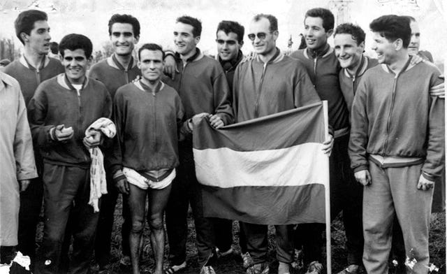 El exatleta Paco Aritmendi tras ganas el Cross de las Naciones en 1964 rodeado de atletas españoles y portando la bandera española.