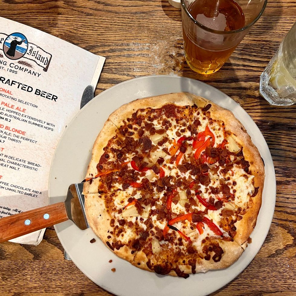 plate of pizza sitting on a wooden table with a craft beer and menu