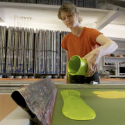 woman pouring neon green paint onto a screen to make wallpaper
