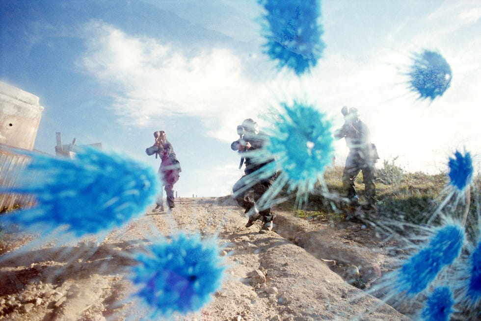 paint ball battle, players in camouflage shooting paint on glass