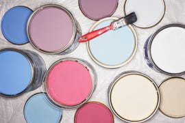 paintbrush balancing on open tins of paint, overhead view, close up