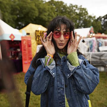 woman puckering and looking away while wearing red sunglasses at market stall during music festival in park