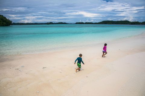 Twee Palauaanse kinderen rennen over een strand op de Rock Islands