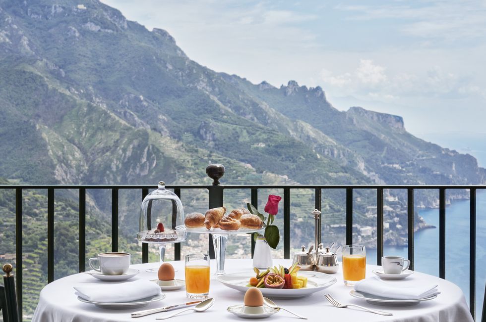a table with food and drinks on it with mountains in the background