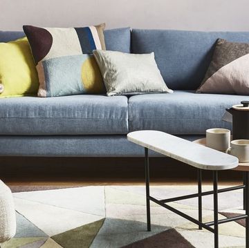 sitting room, living room with blue sofa and multiple coloured cushions and a geometric floor rug