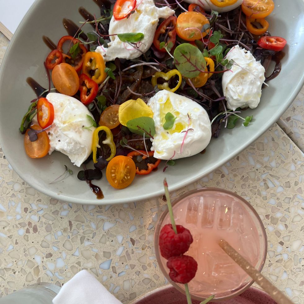 a plate of colorful salad next to a pink cocktail