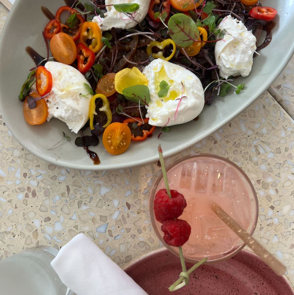 a plate of colorful salad next to a pink cocktail