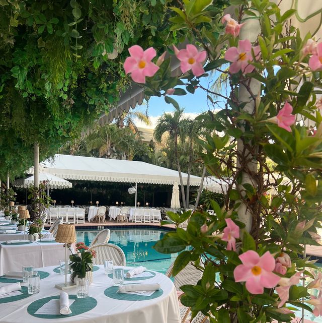 a table with flowers and chairs by the pool