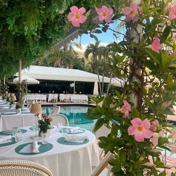 a table with flowers and chairs by the pool