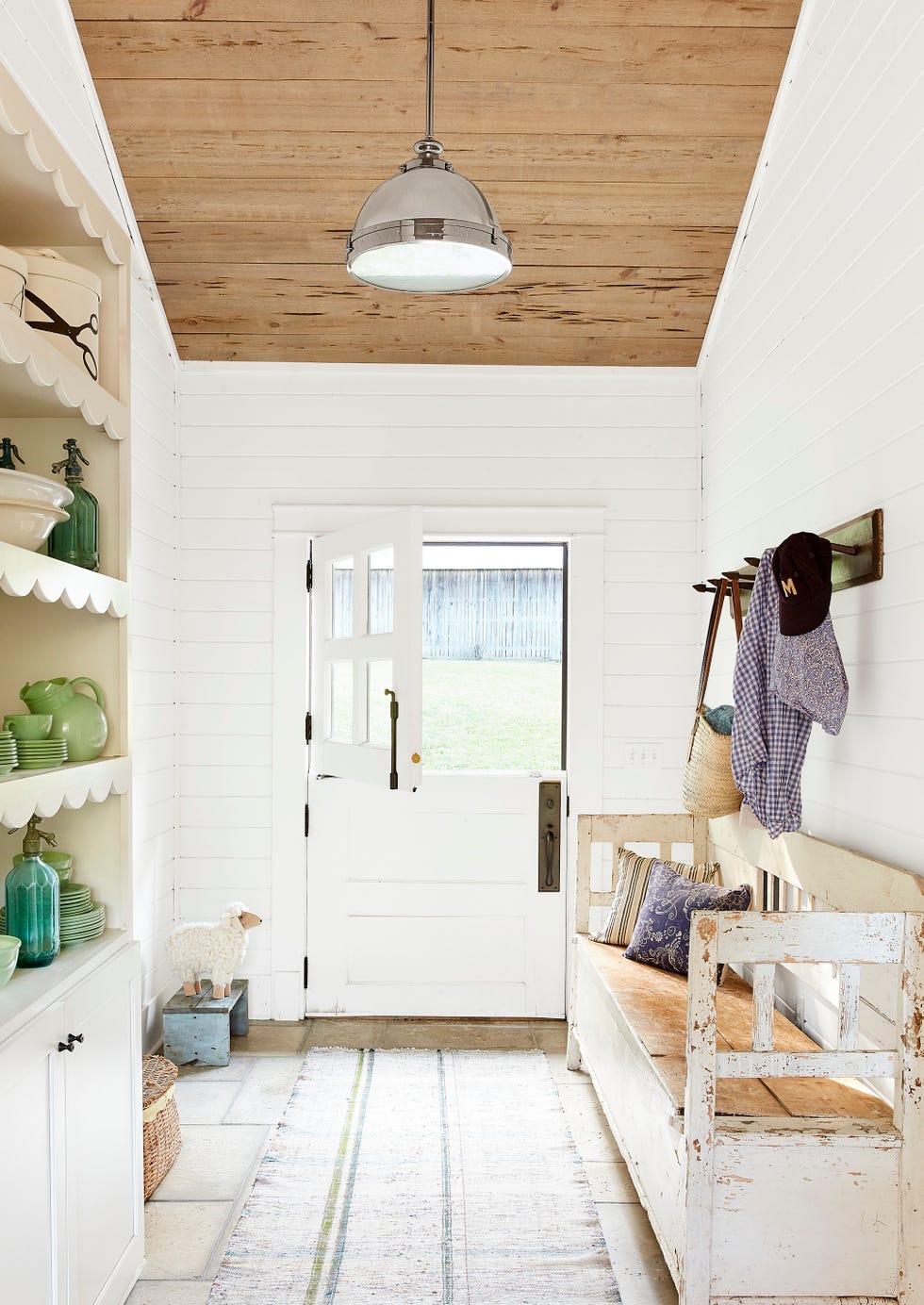 white farmhouse mudroom with dutch door and chippy white bench