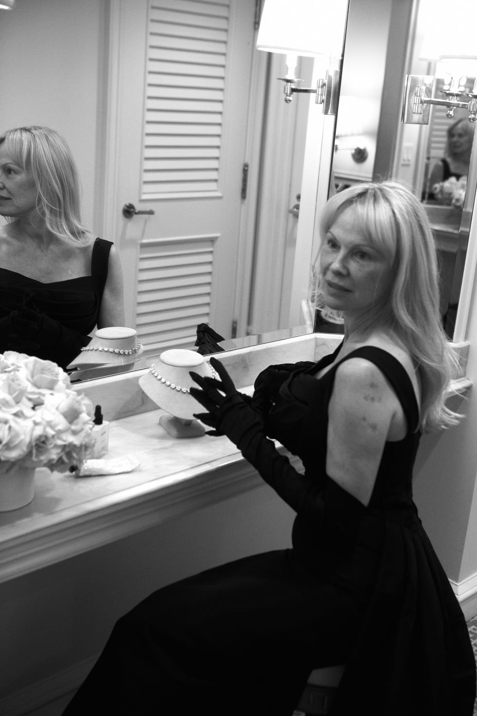 a woman in an elegant black dress sitting at a vanity