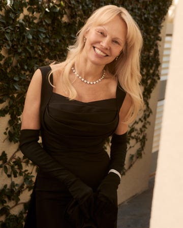 pamela anderson wearing an elegant black dress with long gloves and a diamond necklace