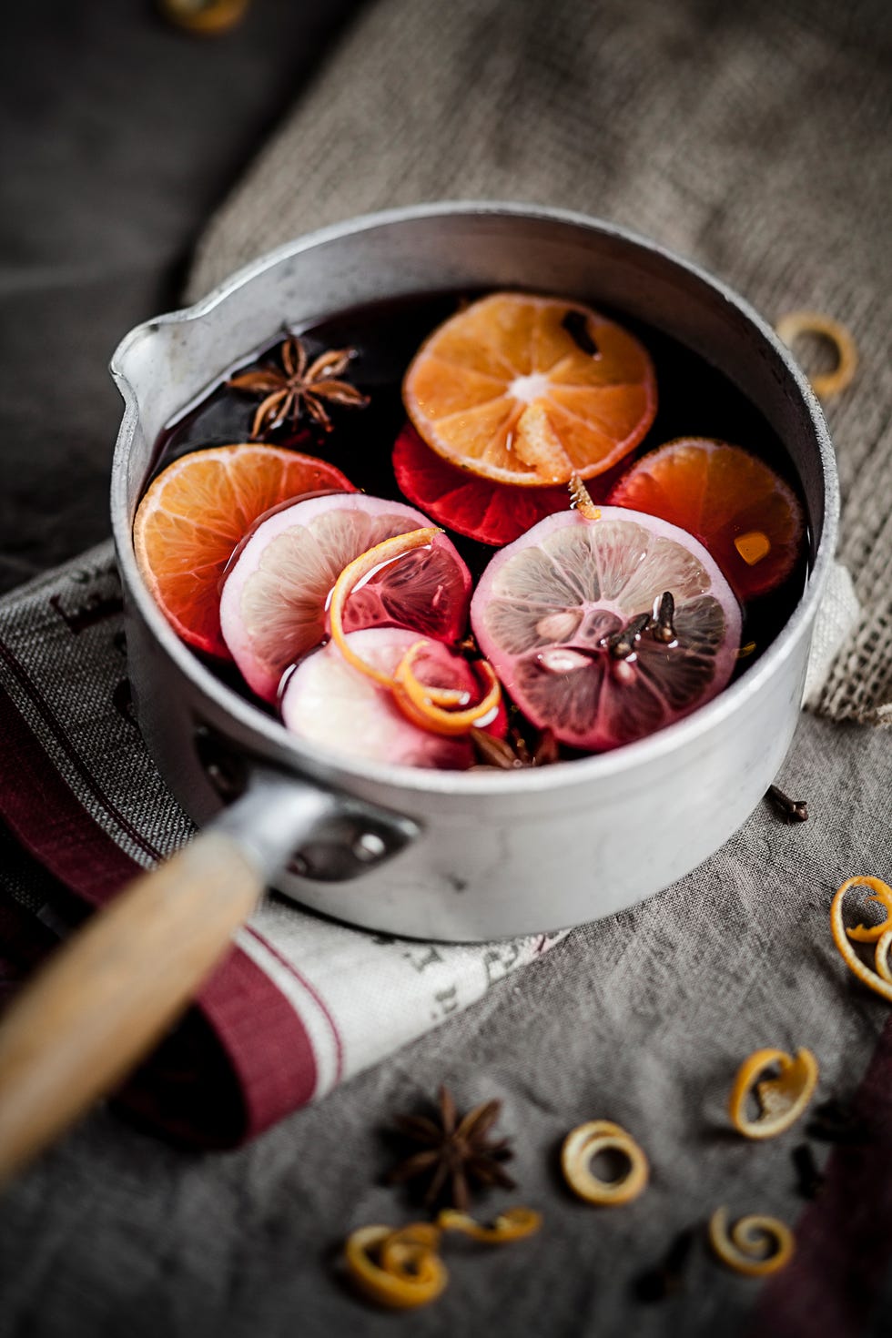 casserole dish featuring mulled wine, lemon and orange slices along with spices