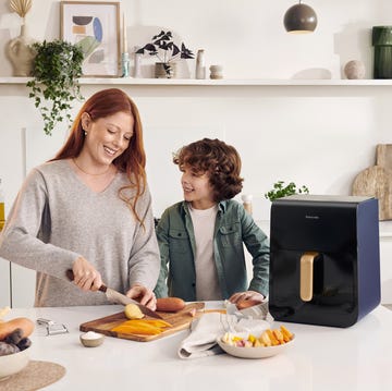 Una mujer corta verduras con una airfryer Panasonic al lado una mujer corta verduras con una airfryer panasonic al lado