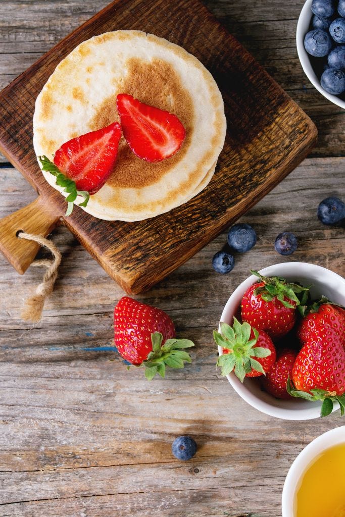 https://hips.hearstapps.com/hmg-prod/images/pancakes-with-strawberries-and-blueberries-bowls-of-honey-news-photo-957729300-1566409658.jpg?crop=1xw:0.37518xh;center,top&resize=1200:*