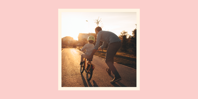 a dad helps supportively while a kid rides a bike