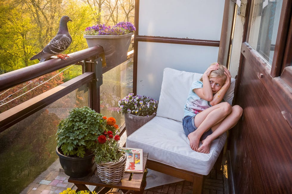 een meisje schrikt van een duif op een balkon