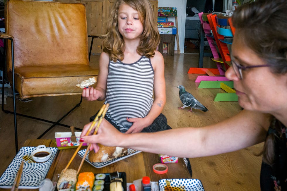 Ollie staat achter de zesjarige Fleur terwijl het gezin afhaalsushi eet Ze vieren de trouwdag van de ouders thuis omdat restaurants nog steeds gesloten zijn Doest hoorde Ollie aankomen lopen in de gang en had zijn camera net op tijd gepakt om deze foto te kunnen maken