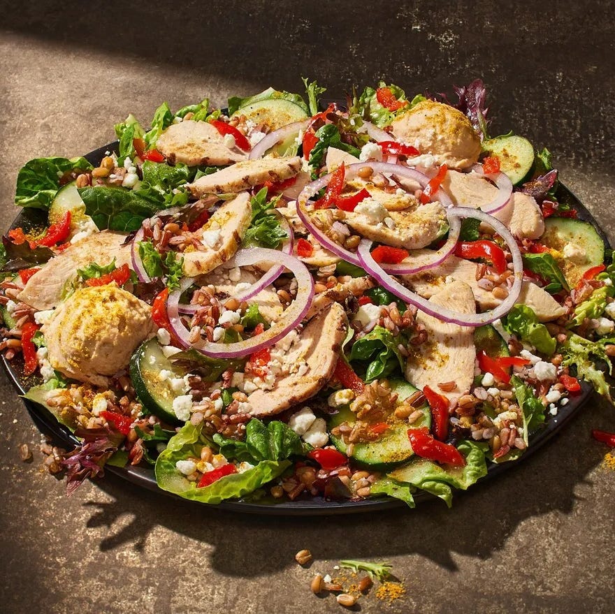 A colorful salad topped with sliced chicken cucumbers and various vegetables a colorful salad topped with sliced chicken cucumbers and various vegetables