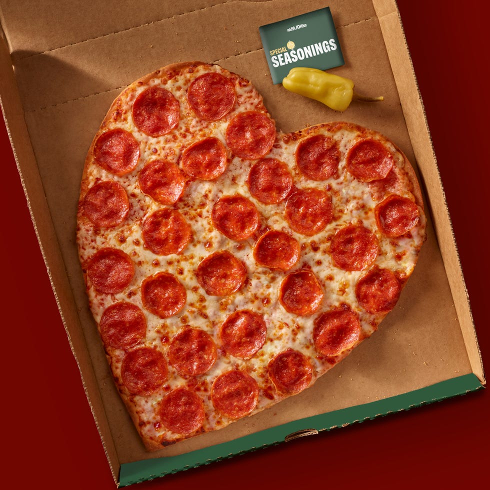 heartshaped pepperoni pizza in a cardboard box with seasoning packet and pepper