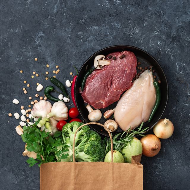 Paper bag food with vegetables, fruit and meat on dark background with copy space top view