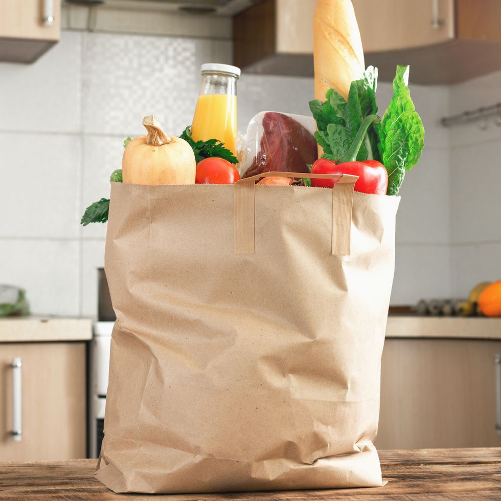 paper bag full of healthy food on a wooden table in the kitchen