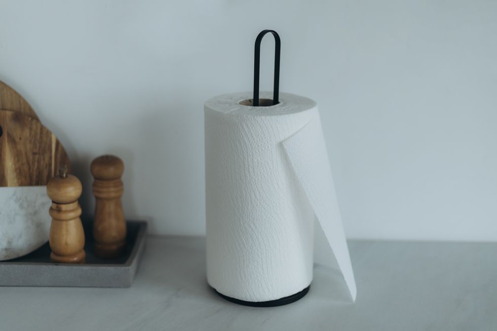 paper towel holder by a tray with wood cutting boards, salt and pepper grinders.
